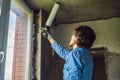 Man in a blue shirt does window installation. Using a mounting foam