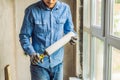 Man in a blue shirt does window installation. Using a mounting foam Royalty Free Stock Photo