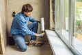 Man in a blue shirt does window installation. Using a mounting foam Royalty Free Stock Photo