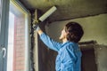 Man in a blue shirt does window installation. Using a mounting foam