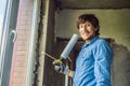 Man in a blue shirt does window installation. Using a mounting foam