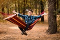 Man in blue shirt and hands up relax in hammock in forest