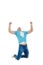 Man in blue shirt and jeans jumping in the air with his hands ra Royalty Free Stock Photo