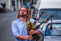 Man in blue shirt playing bagpipes in the street