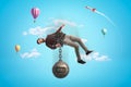 Man in blue sky bound with chains to big metal ball that reads `DEBT` and is pulling him down. Royalty Free Stock Photo