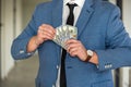 Man in blue suit count stack of dollar bills