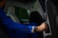 A man in a blue suit opens the car door. Close-up of a man& x27;s hand with an expensive watch. Royalty Free Stock Photo