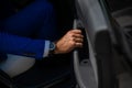 A man in a blue suit opens the car door. Close-up of a man& x27;s hand with an expensive watch. Royalty Free Stock Photo