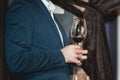 Man in a blue suit with a skin disease holds glass of red wine. people consider the color of the wine and try how it