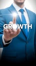 Businessman in blue suit touching virtual button with word growth on white background representing business development and Royalty Free Stock Photo