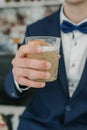 A man in a blue suit and white shirt holds a tall glass of rose wine at an event. natural light Royalty Free Stock Photo