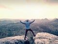 Man in blue sweatshirt with raised arms gesture triumph on exposed cliff Royalty Free Stock Photo