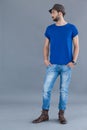 Man in blue t-shirt and fedora hat posing with hands in his pockets Royalty Free Stock Photo