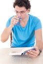 Man in blue t-shirt with glasses sitting at table and reading bo Royalty Free Stock Photo