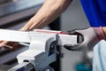 A man in a blue T-shirt and gray gloves clamps a part in a vice, a worker at a workbench