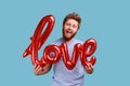 Man in blue T-shirt holding love word of foil balloons expressing positive emotions and his feelings Royalty Free Stock Photo