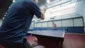 Man in blue T-shirt playing a ping-pong with woman at the court