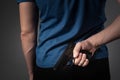 A man in a blue T-shirt pulls a gun behind his back Royalty Free Stock Photo