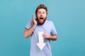 Man in blue T-shirt showing white arrow pointing down expressing shocked emotions, downgrade concept Royalty Free Stock Photo