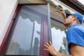 Man installing mosquito net wire screen on terrace doors Royalty Free Stock Photo