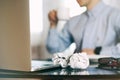 Man in blur, laptop, coffee cup and crumpled wads on table. new idea