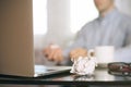 Man in blur, laptop, coffee cup and crumpled wads on table. new idea