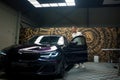 Man with a BMW parked in a Contemporary European Garage, Artistic Mural Adorns