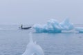 Man on a boat between bizarre ice floes of Iceberg lagoon jokulsarlon on the south of Iceland Royalty Free Stock Photo