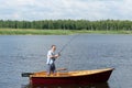 A man in a boat on a river rejoices when a fish is caught spinning while pulling it out of the water Royalty Free Stock Photo