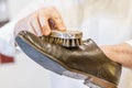 Man body and hand restoring parisian brown leather shoes.