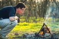 Man and bonfire in spring forest. Coals of fire. Sunset