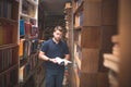 Man with a book in his hands stands in an atmospheric public library and looks at the camera Royalty Free Stock Photo