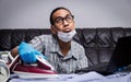 man with boring face working with very busy business and housework part ironing cloth and working with laptop Royalty Free Stock Photo