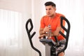 Man with bottle resting after training on modern elliptical machine indoors Royalty Free Stock Photo