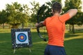 Man with bow and arrow aiming at archery target in park, back view Royalty Free Stock Photo