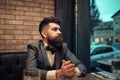 Man in a bow tie. Confident bar customer sit in cafe and thinking. Date meeting of hipster awaiting in pub. Business on Royalty Free Stock Photo