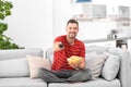 Man with bowl of potato chips watching TV on sofa Royalty Free Stock Photo