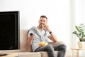 Man with bowl of potato chips watching TV on sofa Royalty Free Stock Photo