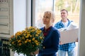 Man with box and woman with flowers entering new house Royalty Free Stock Photo