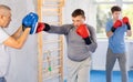 Man in boxing gloves practicing punches on mitts during self-defense course