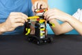 A man and a boy assemble from a constructor of a robot. Male and children`s hands collect lego