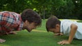 Man and boy doing push ups in meadow. Cheerful father and son training together Royalty Free Stock Photo