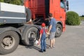 man and a boy, father and son, stand in front of a large truck, examining its mechanism