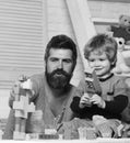 Man and boy play with toy gun on wooden wall background. Father and son with happy faces create colorful constructions Royalty Free Stock Photo