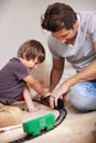 Man, boy and playing with train toys, together for family time and fun with plastic railway track at home. Father, child Royalty Free Stock Photo