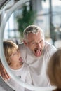 Man and a boy showing tongues to the mirror Royalty Free Stock Photo