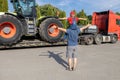 man and a boy stand in front of a large tractor standing on a truck trailer