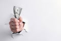 Man breaking through white paper with money in fist, closeup. Space for text Royalty Free Stock Photo