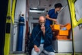 Man breathe through oxygen mask, young nurse packs equipment in medical bag in the ambulance car