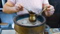 A man brews a Turkish coffee on the sand in the pot, hands close up. Coffee made on the sand in ibrik or ibriq. Coffee Royalty Free Stock Photo